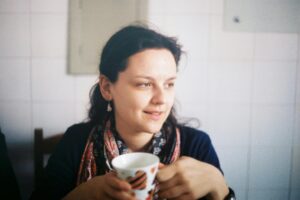 A young woman enjoying a cup of coffee indoors, captured in natural light.